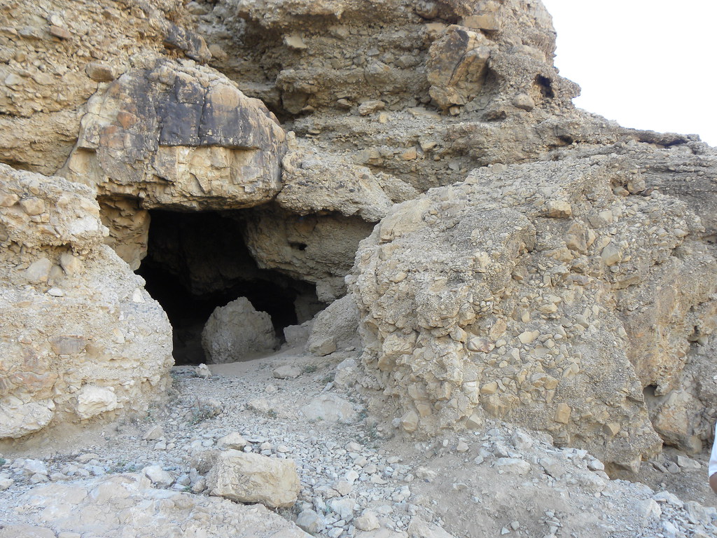 The mouth of a cave atop a desert plateau.