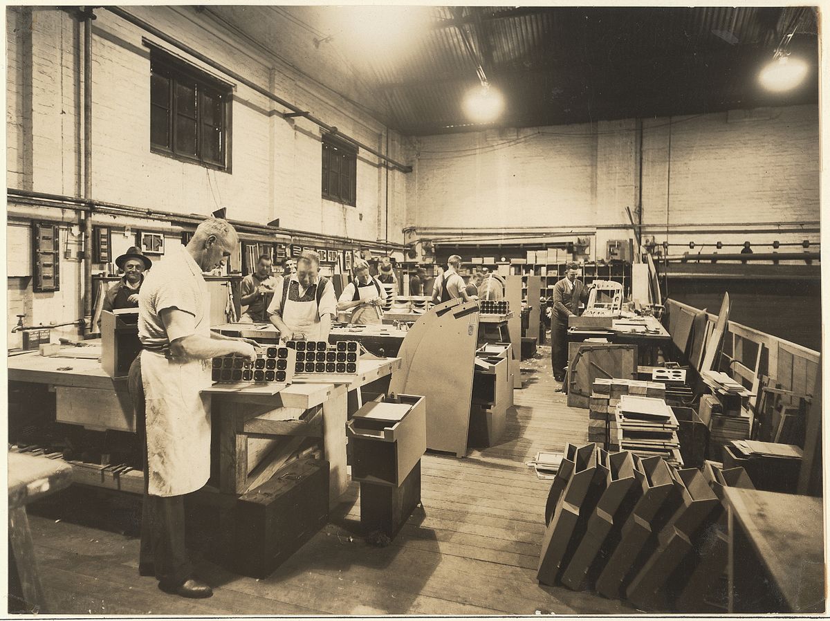 一张黑白照片，几名男子在不同工作台上操作机械装置